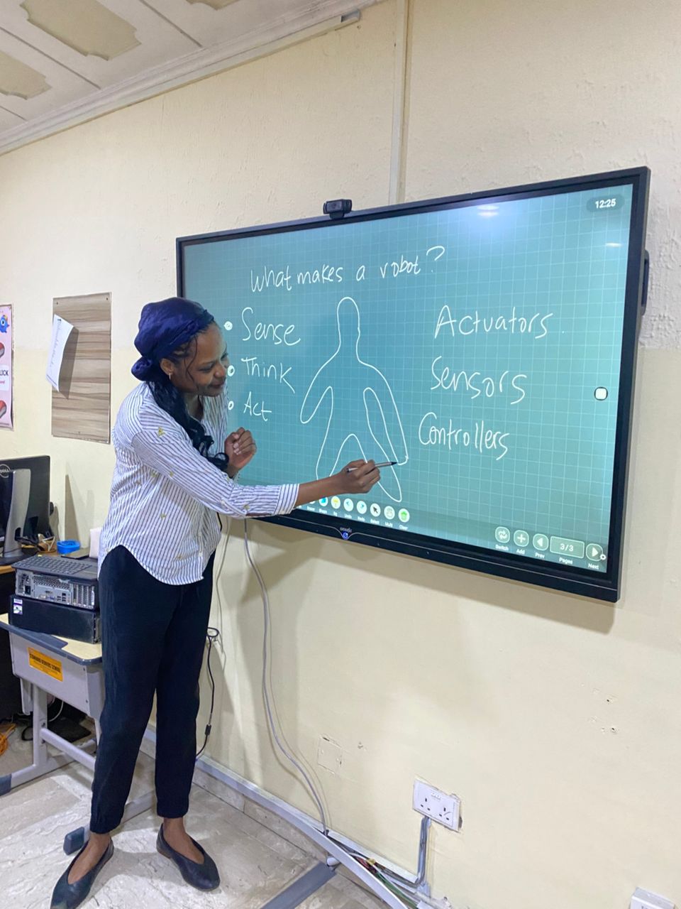 Instructor diagramming 'What makes a robot?' — Sense, Think, Act — on a smartboard